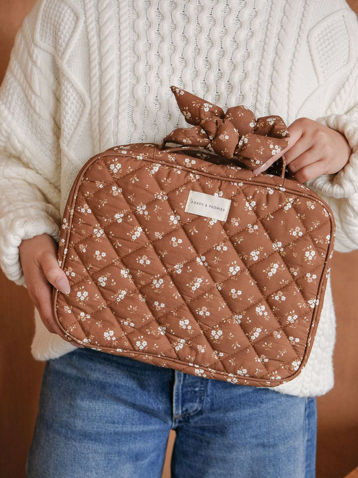 Lifestyle close-up of the Hook Me Up Cosmetic Case in Brown Floral, showcasing its roomy rectangular shape, quilted cotton finish, floral print, and top handle.