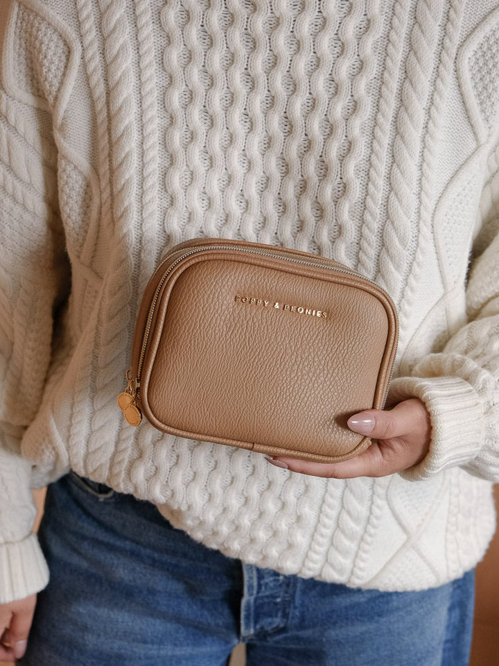 Lifestyle shot of the Poppy & Peonies Pretty Connected Case in Mocha Mousse, held against the body to show its compact size and portability.