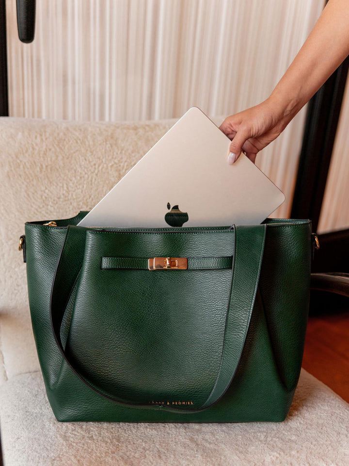 Green handbag with a laptop being placed inside, on a neutral background