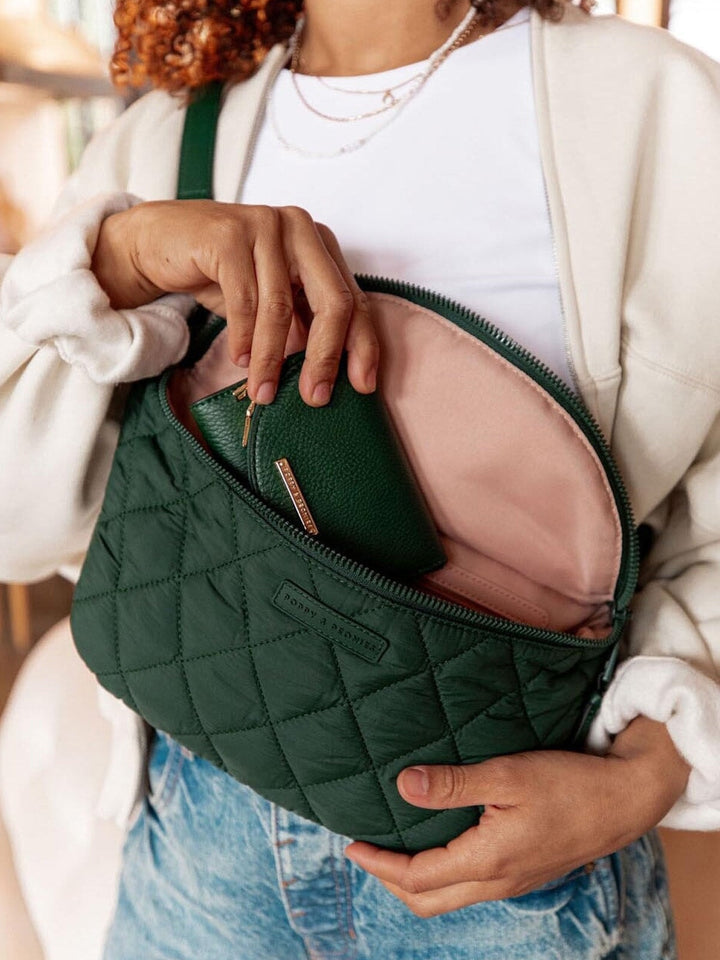 Person holding a green quilted handbag with a visible brand logo.