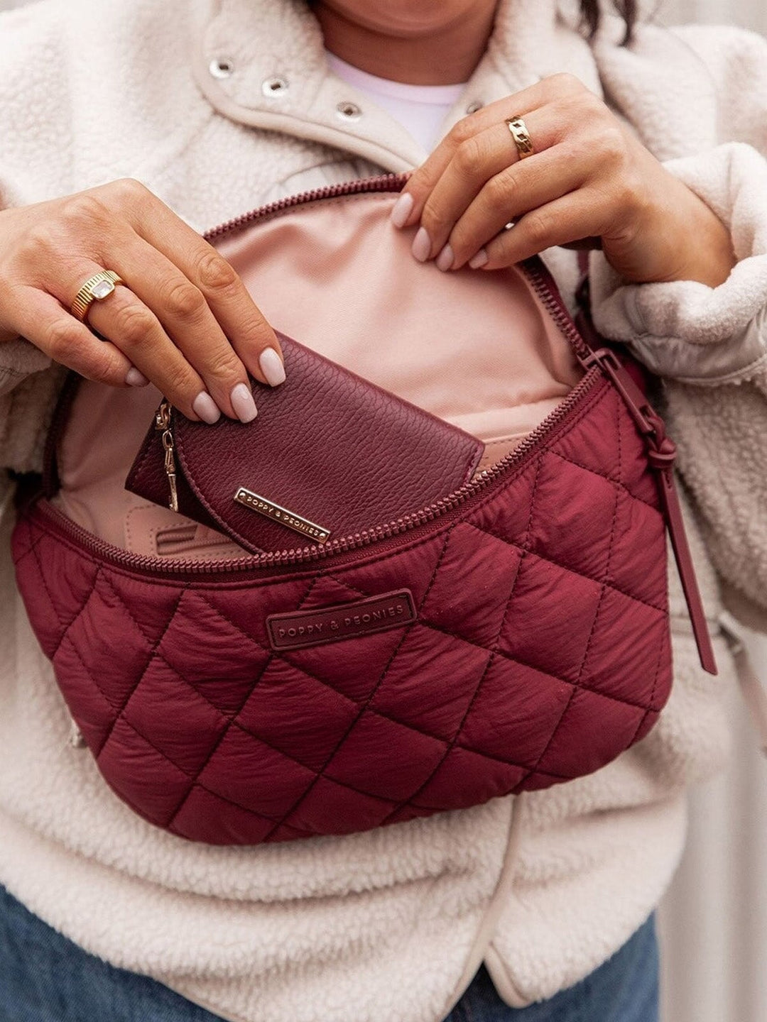 Person holding a quilted coloured crossbody bag with a visible brand logo.