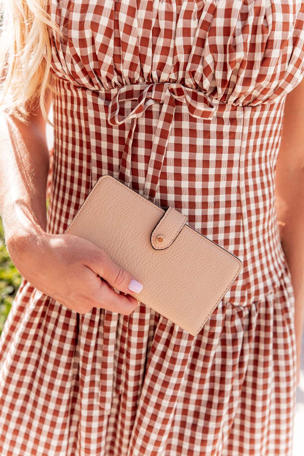 Woman holding a Poppy & Peonies Go Anywhere Wallet in sand colour