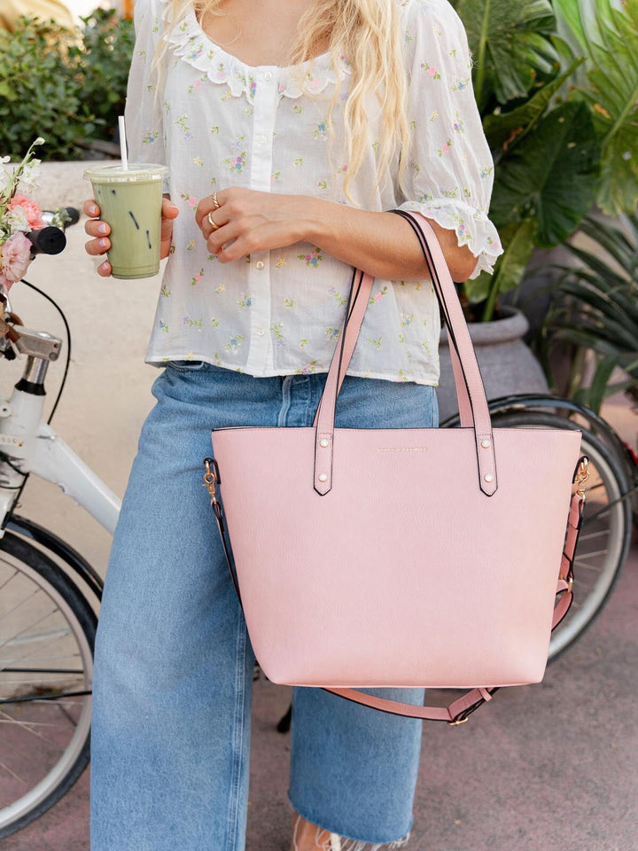 Person holding a pink tote bag with a blurred background