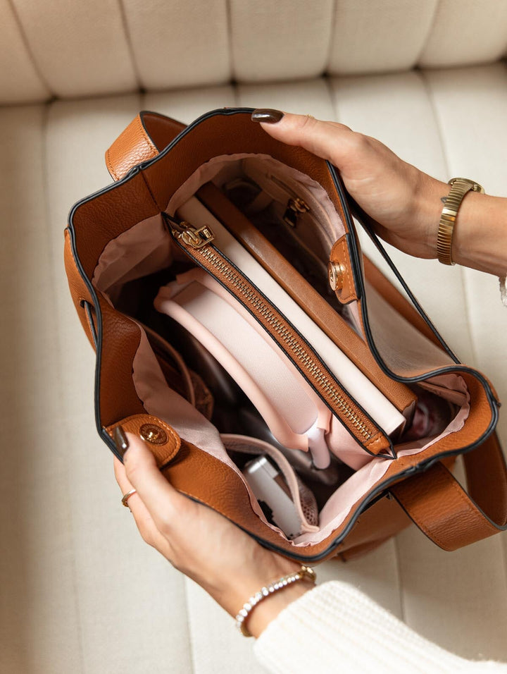 Poppy & Peonies The Knot Shoulder Bag in Cognac, overhead view showing the open interior with blush-pink lining, zippered organizer, and everyday essentials.