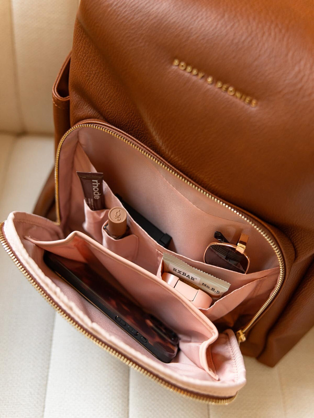 Poppy & Peonies The Cabin Backpack in Chestnut, close-up of the open front zippered organizer showing blush-pink lining, slip pockets, and small everyday essentials.