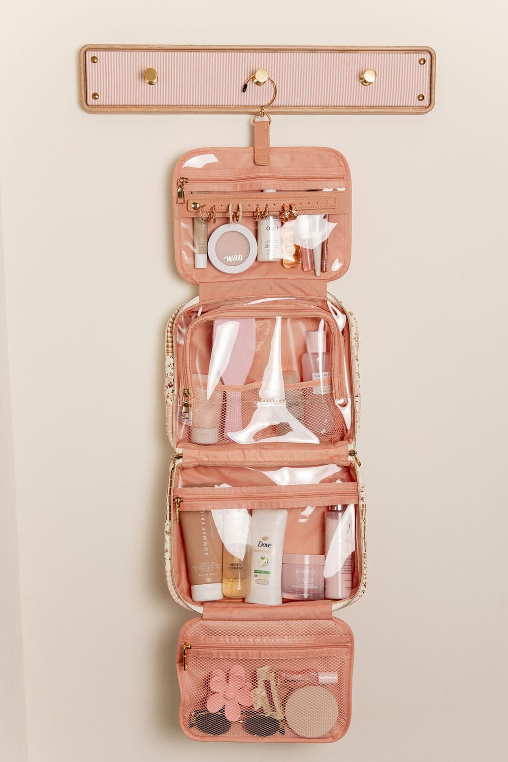 Pink hanging travel organizer with toiletries on a beige background