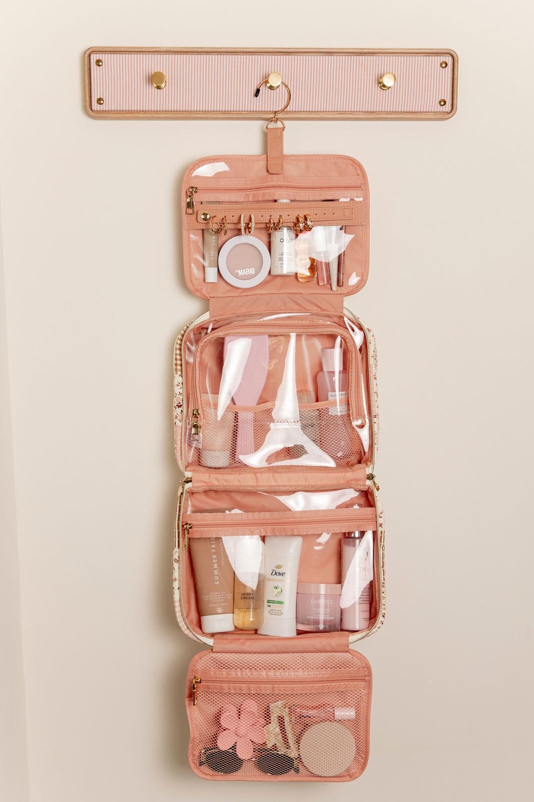 Pink hanging travel organizer with toiletries on a beige background
