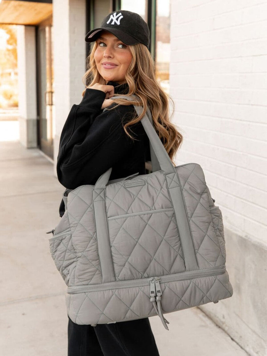 Woman holding a grey quilted bag outdoors
