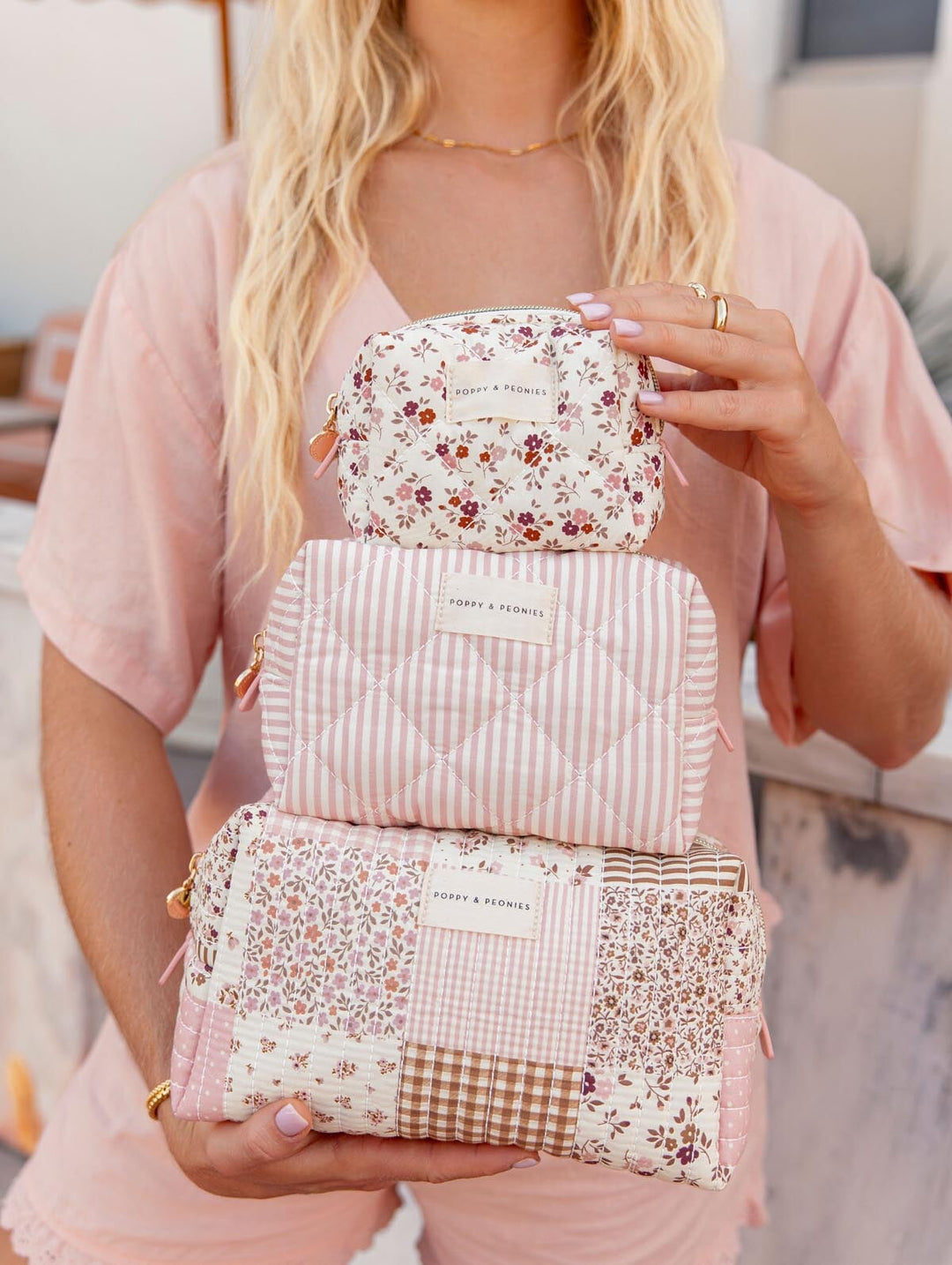 Person holding three floral-patterned cosmetic cases