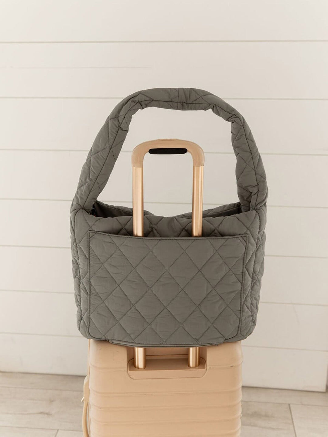 Quilted grey hobo bag with a trolley sleeve  on a suitcase